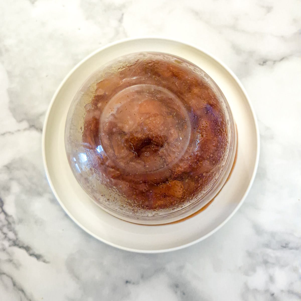 An inverted dish of strawberry sponge pudding on a white plate.