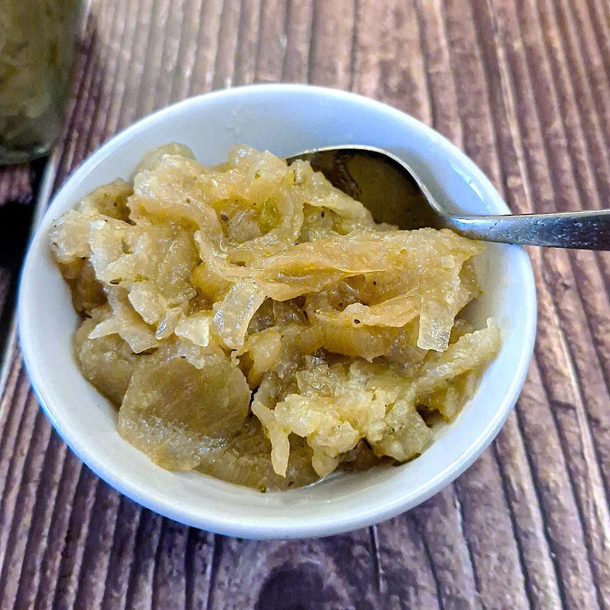 A small white dish of onion and apple marmalade with a spoon