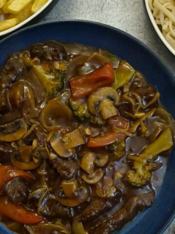 A serving dish filled with rump steak strips in a thick garlic sauce.