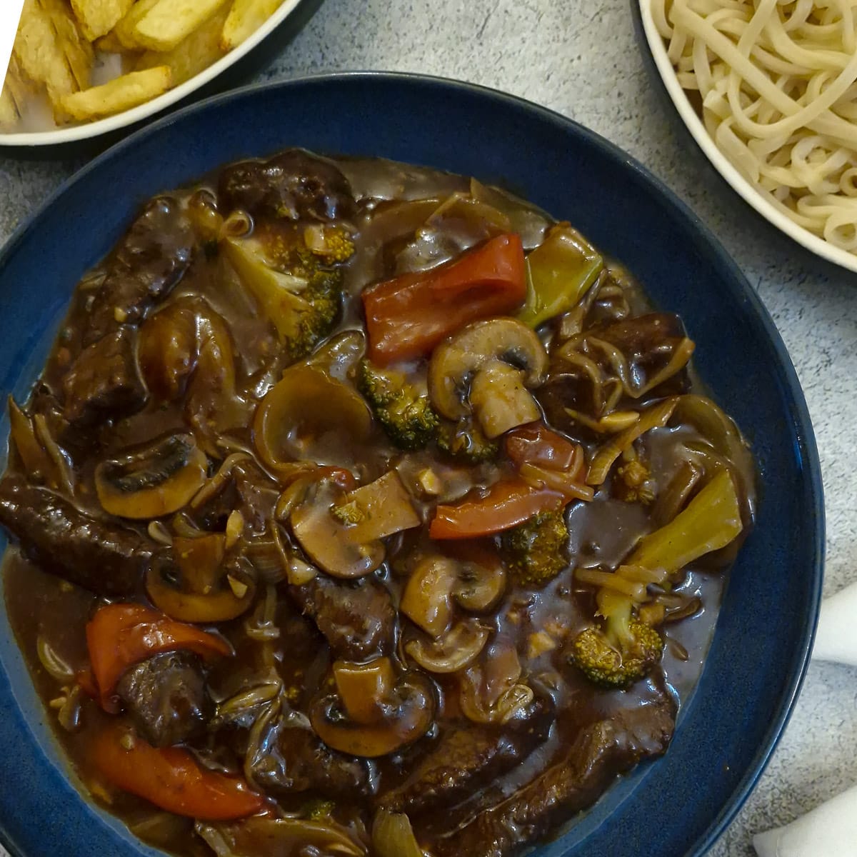 A serving dish filled with rump steak strips in a thick garlic sauce.