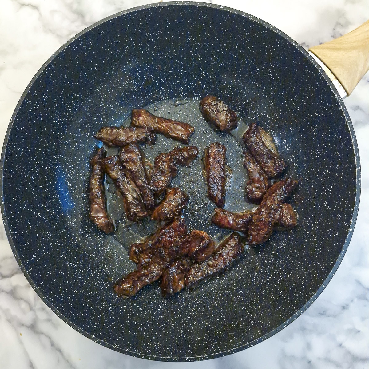 Steak strips browning in a wok.
