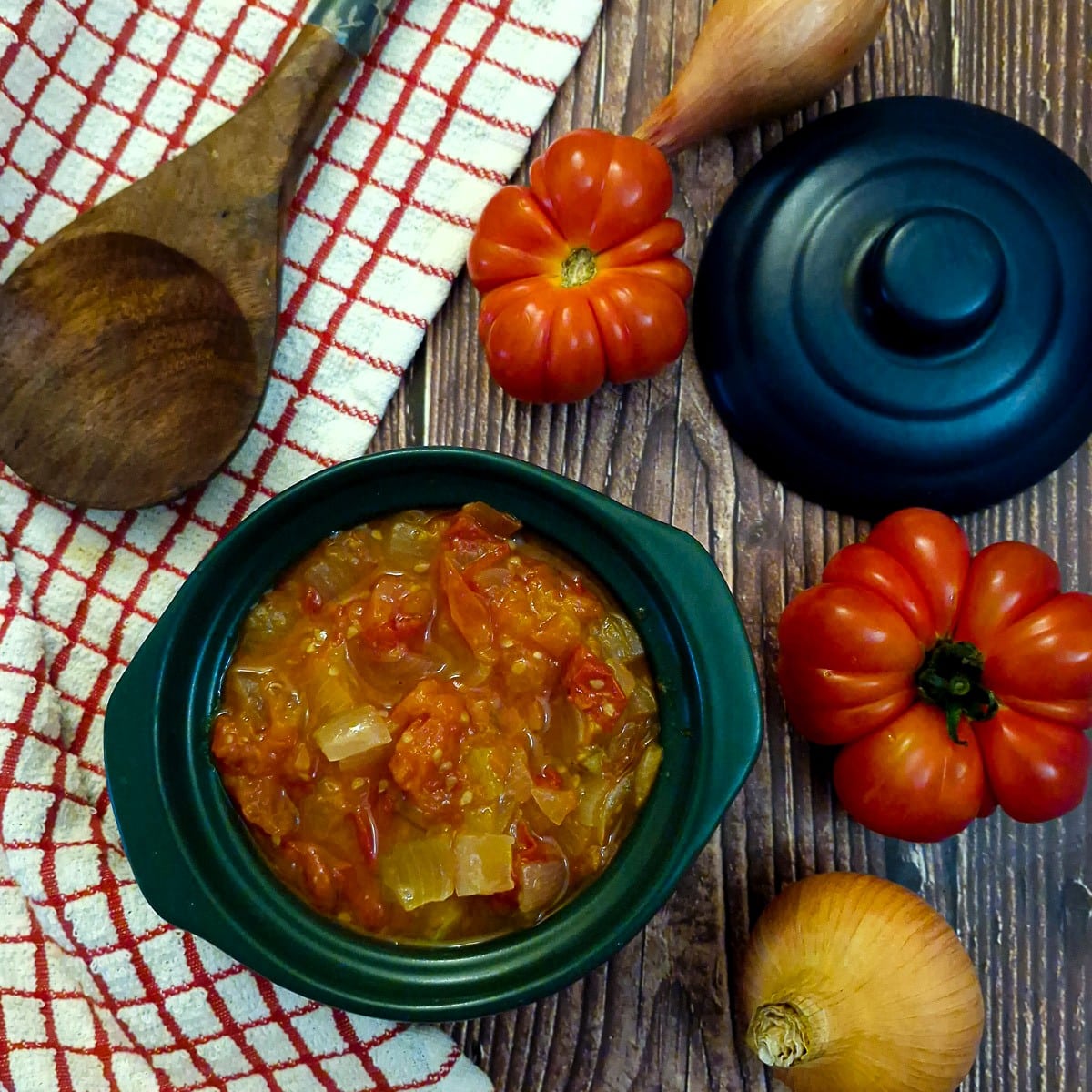 A dish of tamitie-smoor on a table with tomatoes and onions.