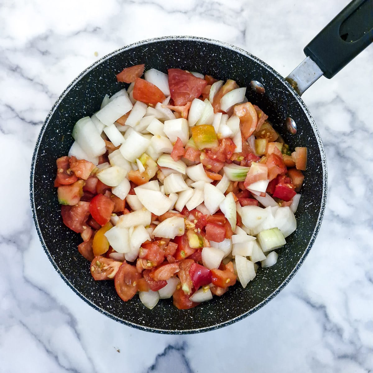 Chopped tomatoes and onions in a large pan.