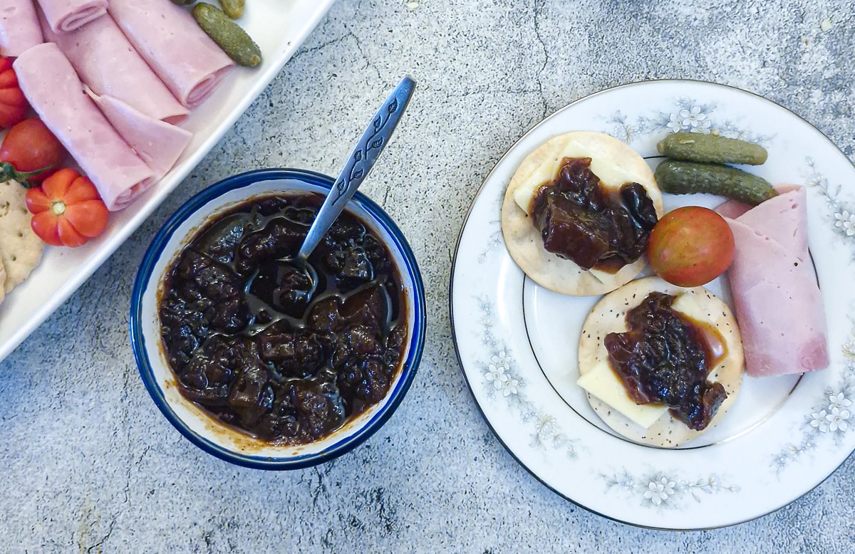Overhead shot of a ish of marrow and apple chutney next to a side plate of ham, gherkins, cheese and chutney.