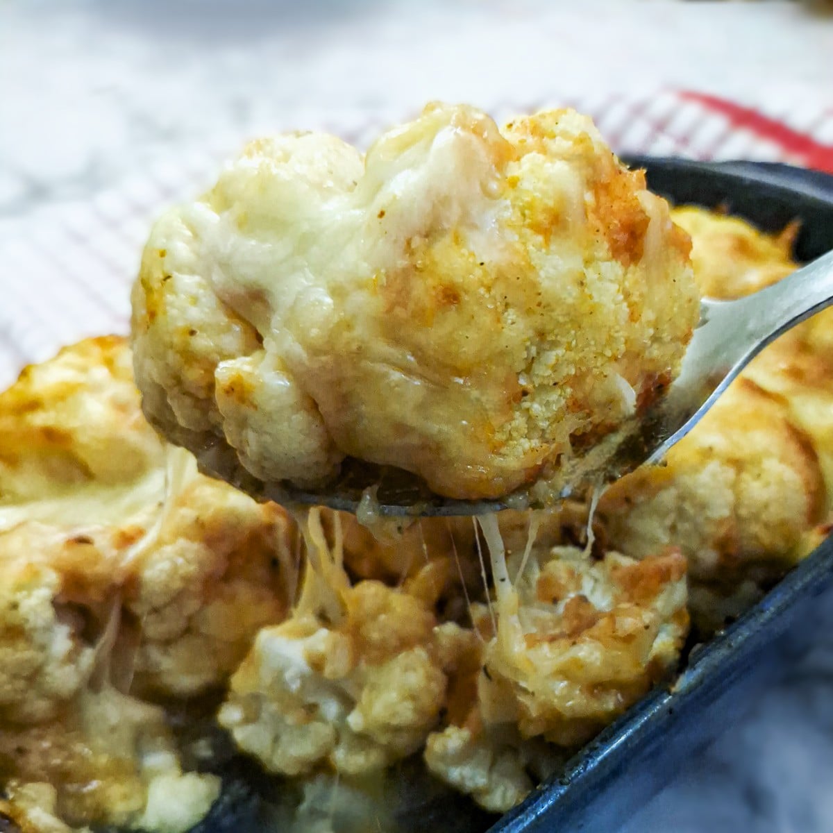 A spoonful of cauliflower held above the serving dish.
