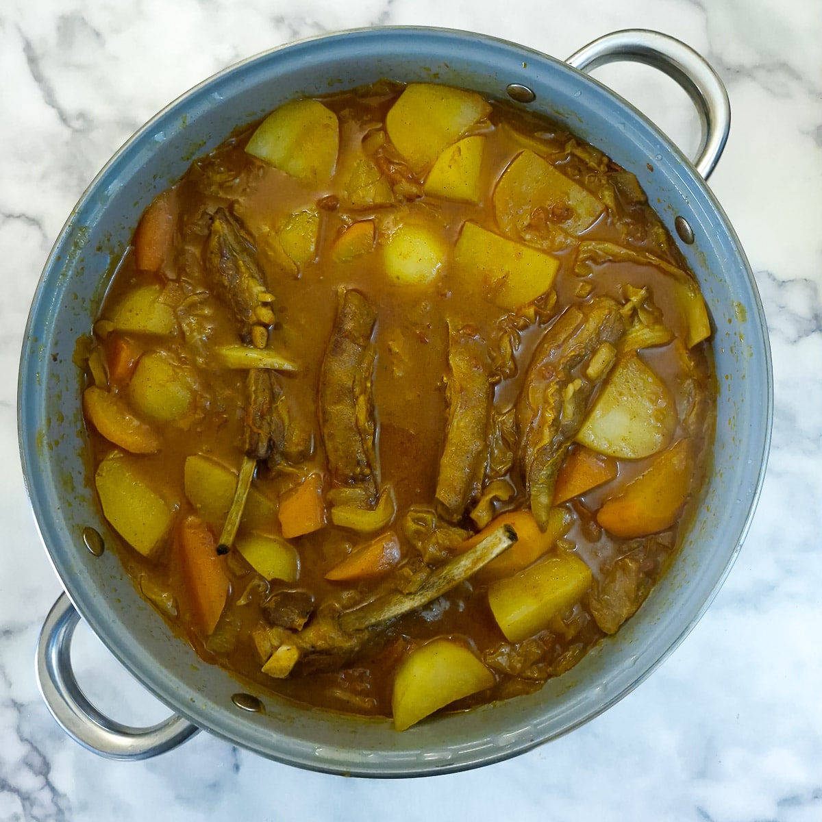 Step 10, a fully cooked lamb rib curry in a large saute pan.