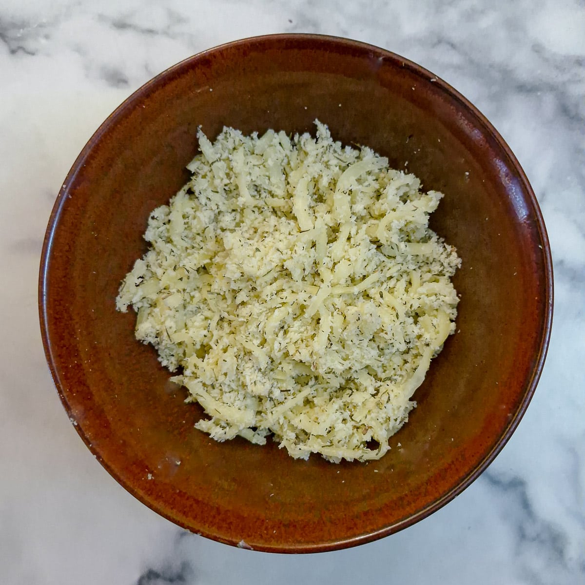 Step 12, breadcrumbs and grated cheese combined in a small brown bowl.
