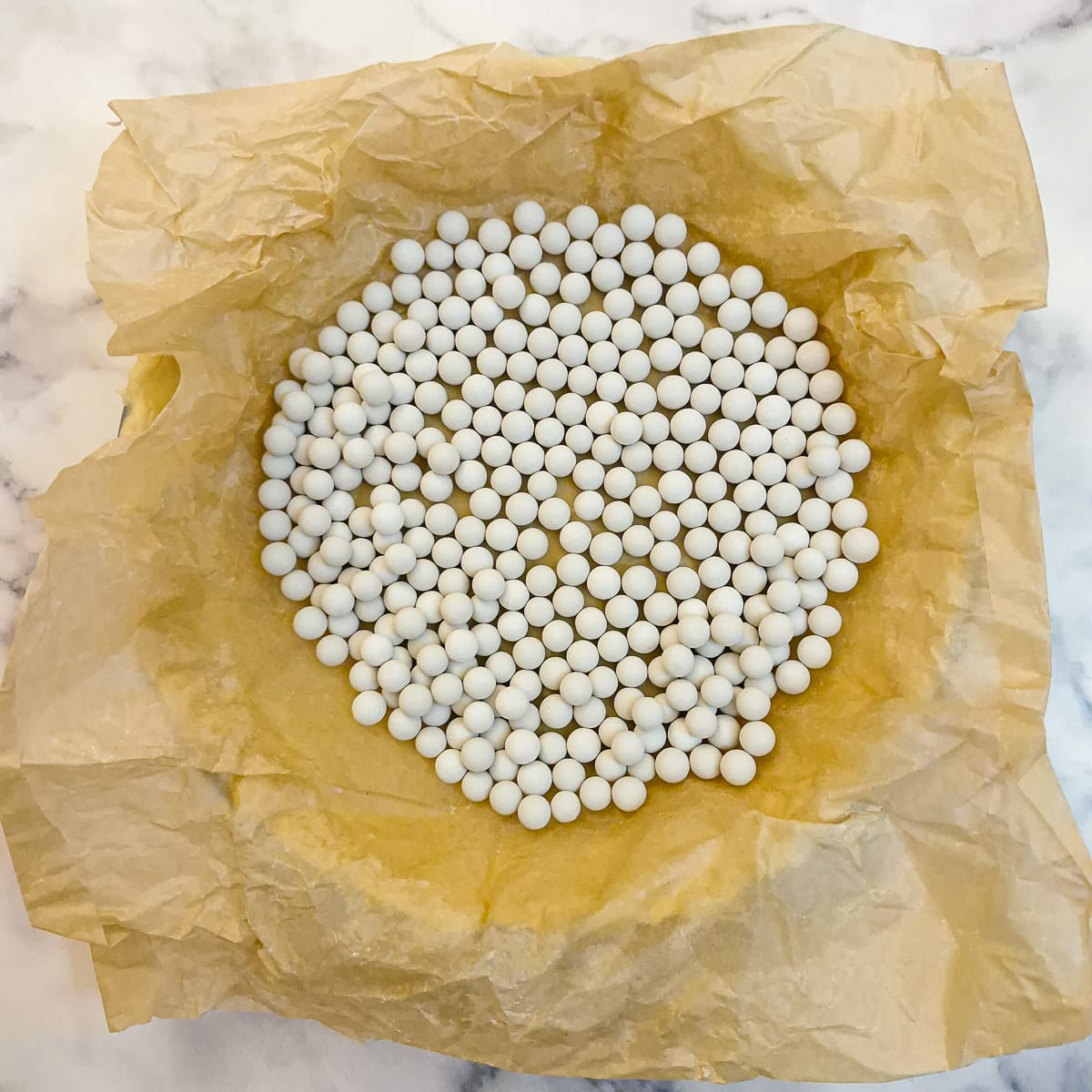 Step 8, Baking beans on top of baking parchment covering the pastry in a pie dish.