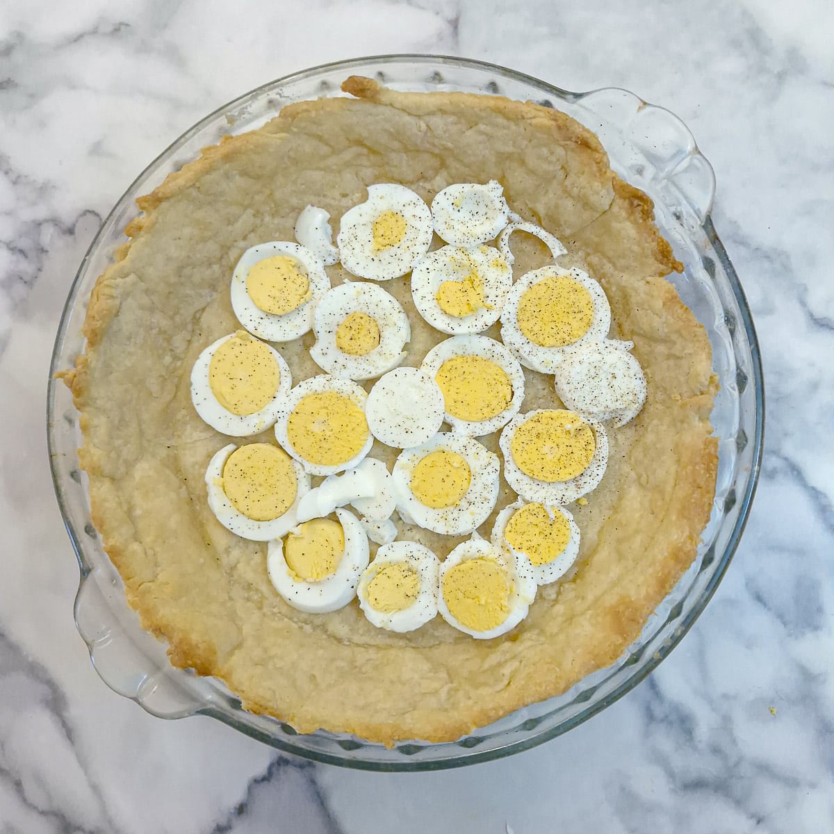 Step 9, slices of boiled egg arranged on the baked pastry in a pie dish.