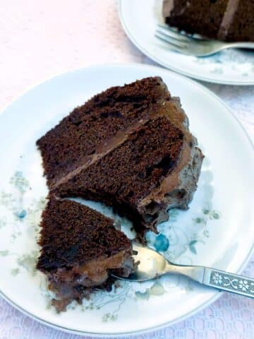 A slice of peppermint chocolate cake on a flower-patterned plate with a cake fork cutting through the corner.