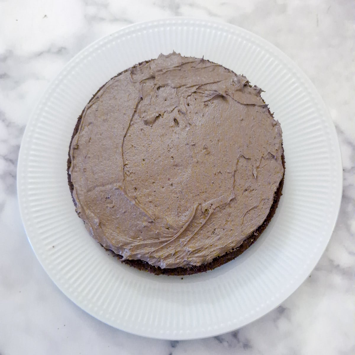 Step 13, buttercream spread over the bottom layer of the cake.