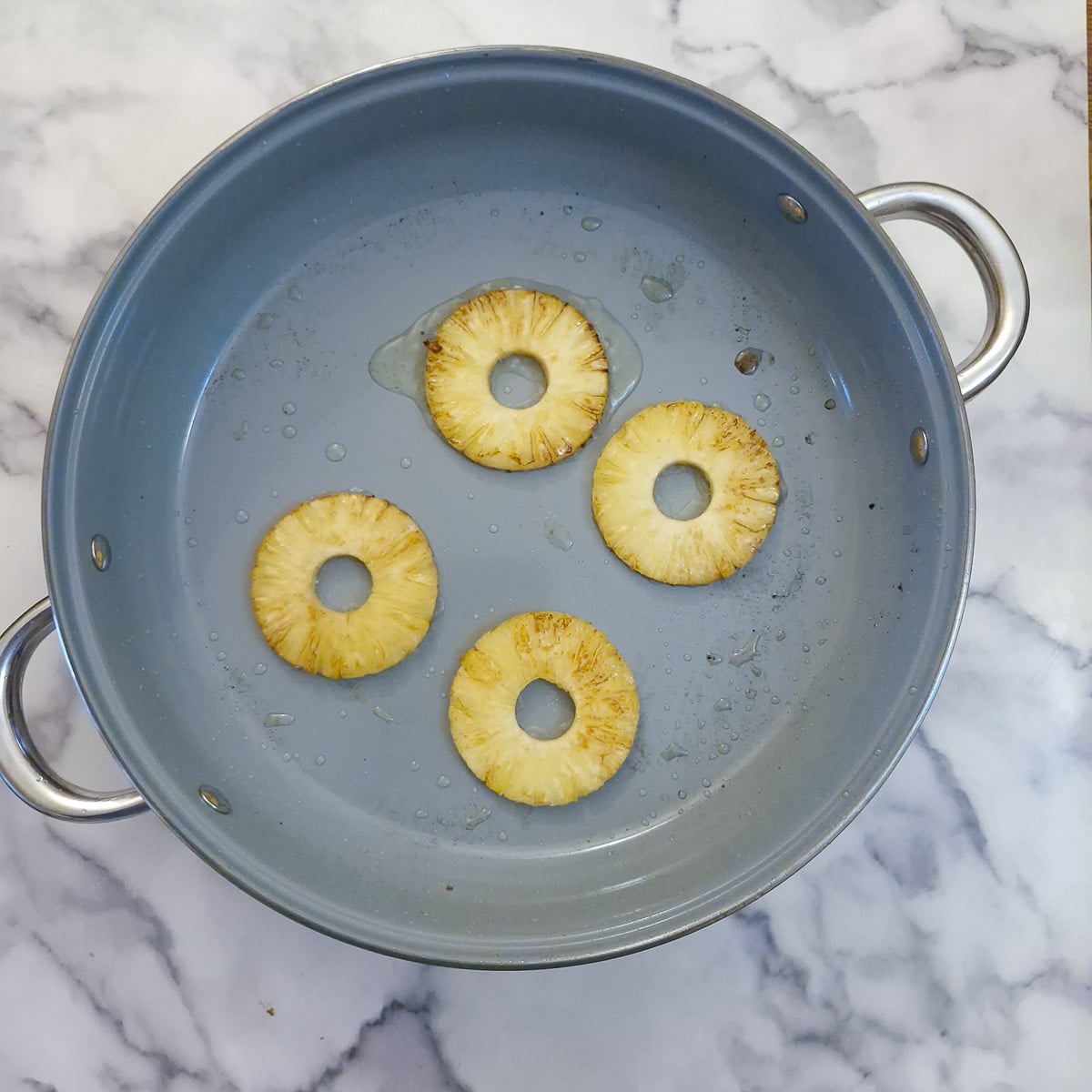 4 pneapple rings browning in a large pan.