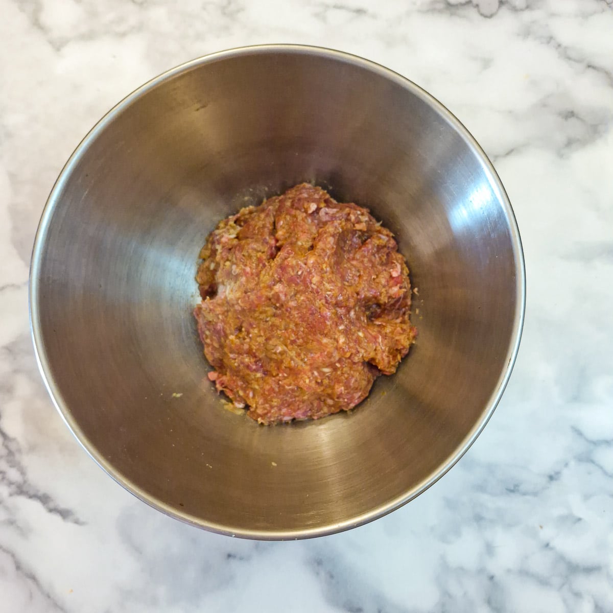 Step 4, a ball of raw mince meat that has been mixed with egg, breadcrumbs and seasoning ready to be formed into patties.
