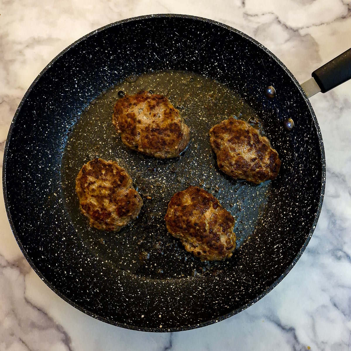 Step 6, 4 patties browning in a frying pan.