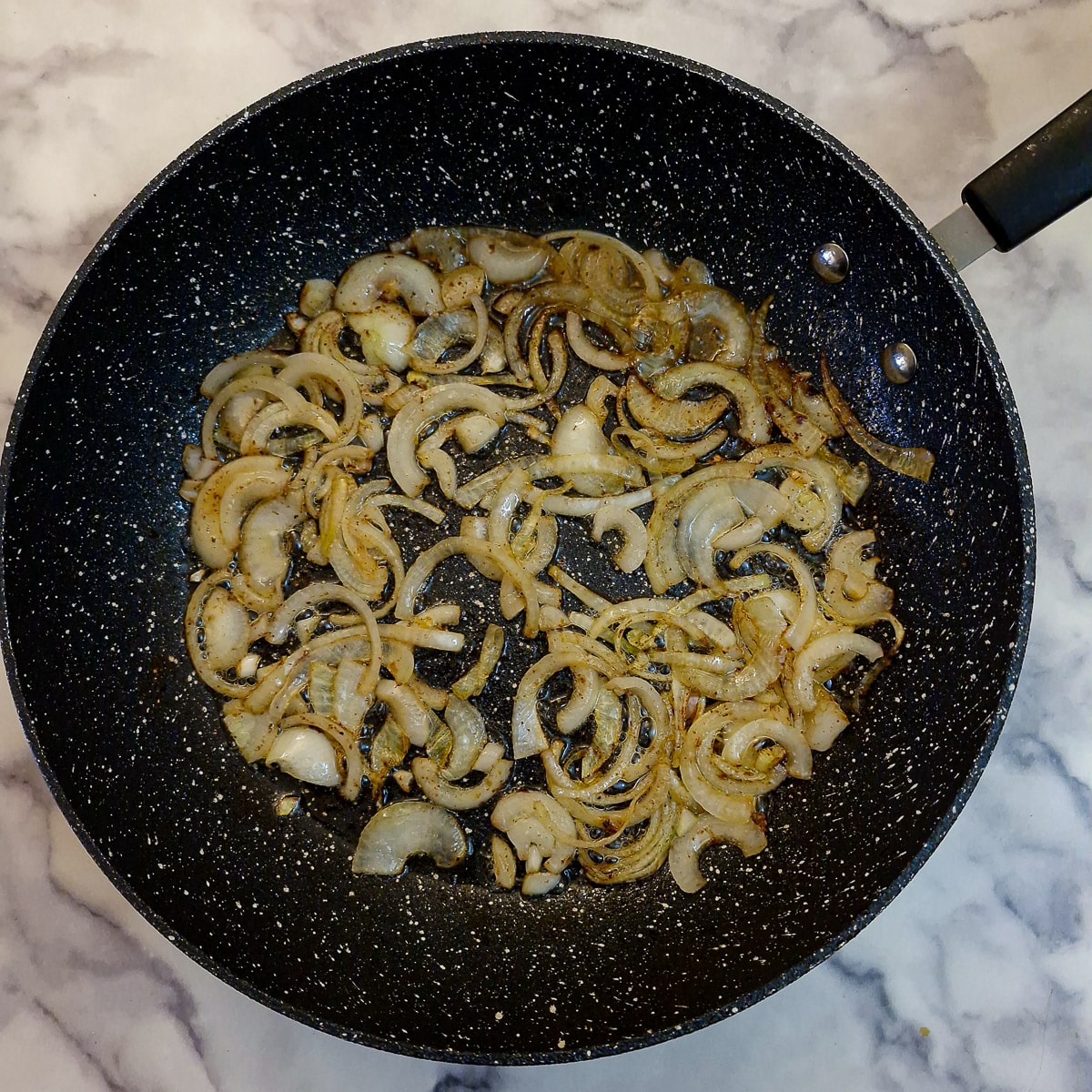 Step 7, sliced onions softening in a pan.