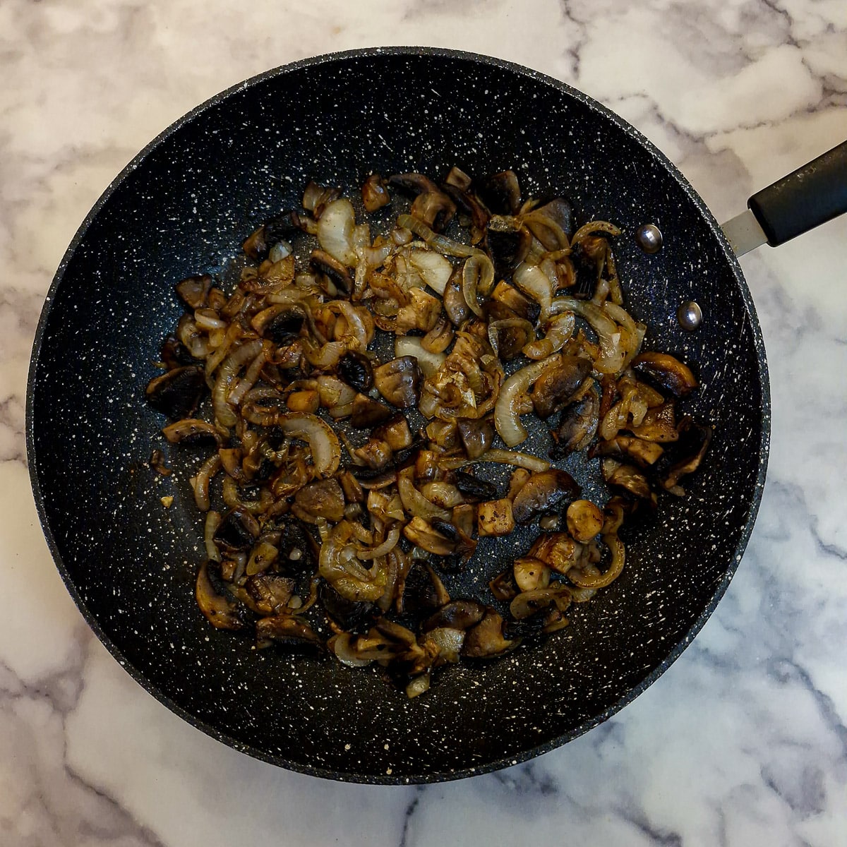 Step 8, mushrooms softening with the onions in a pan.