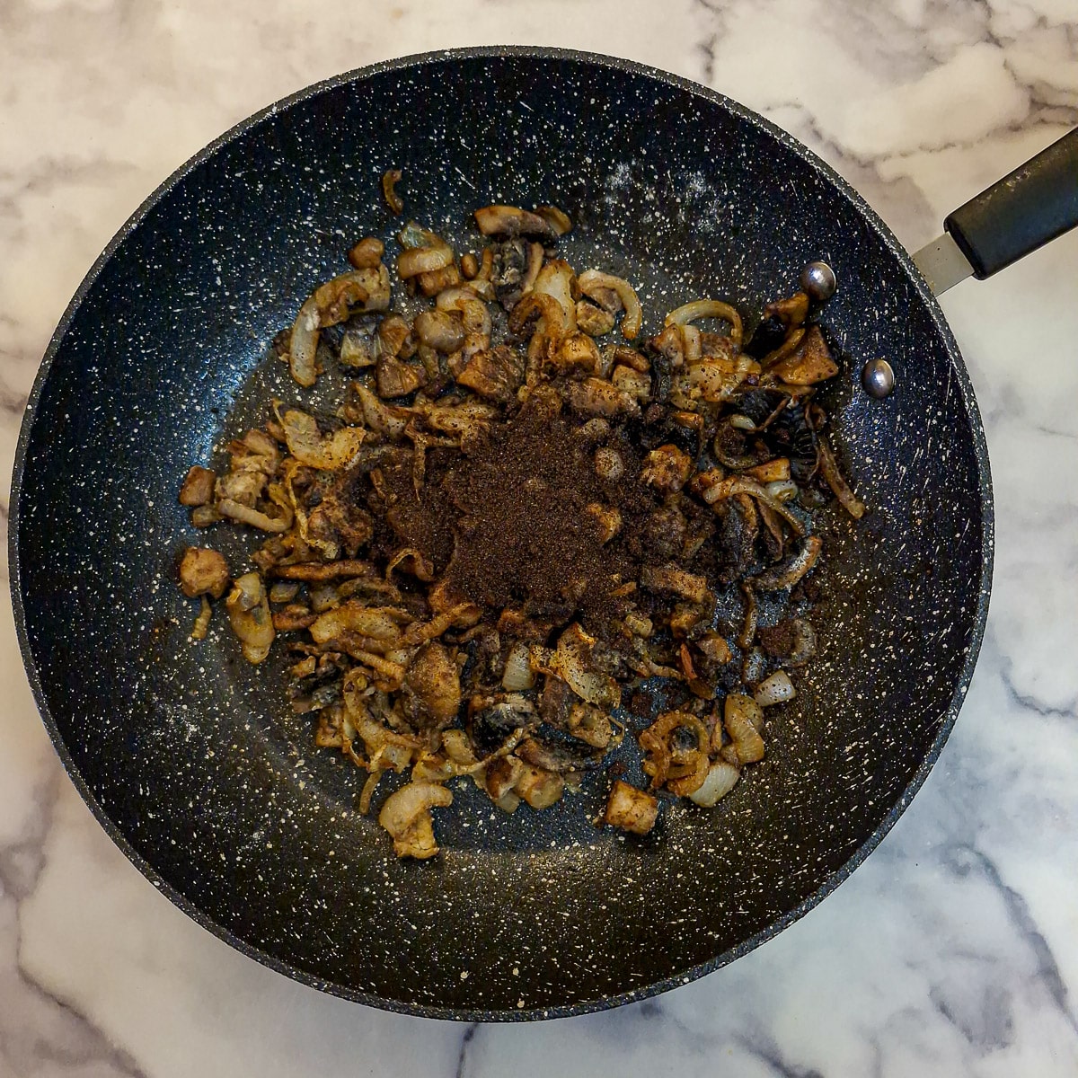 Step 9, 2 oxo cubes crumbled on top of the mushrooms and onions.