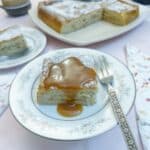 A slice of caramelised banana magic cake on a blue patterned plate, drizzled with caramel sauce.