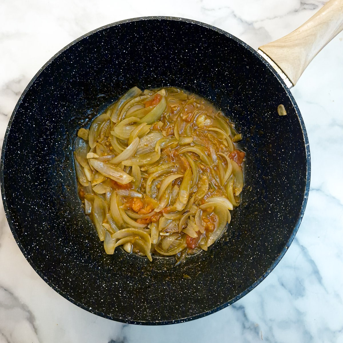 Onions and tomatoes softening in a wok.