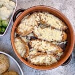 A brown cassrole dish of French onion beef stew topped with slices of cheesy bread.