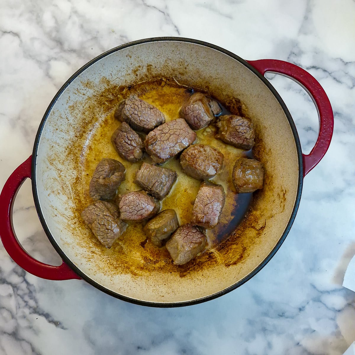 Pieces of beef browning in a Dutch oven casserole.