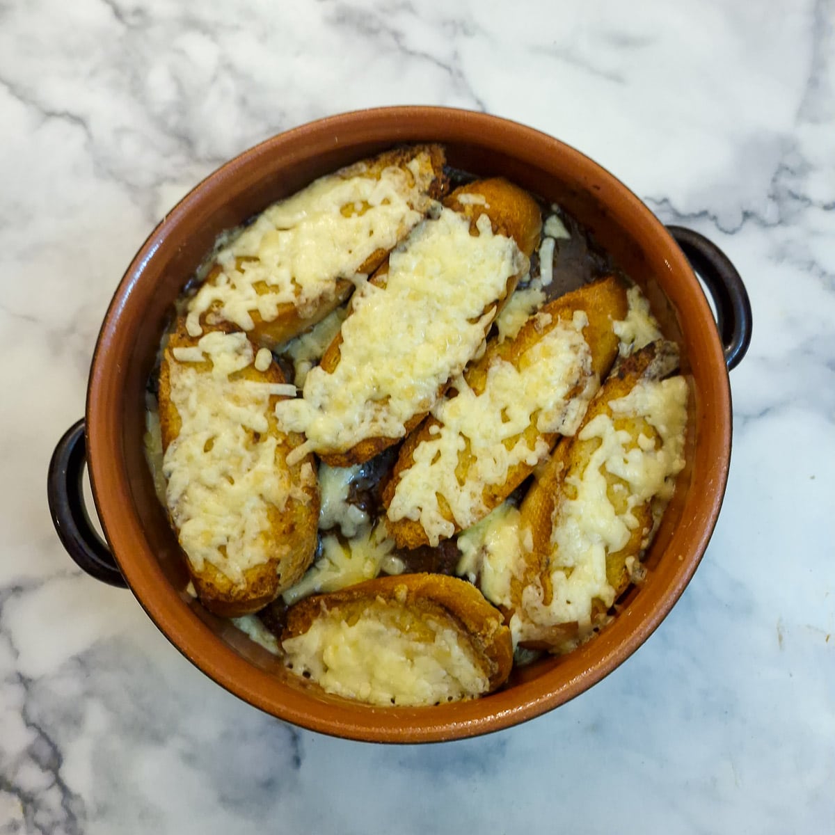 The fully cooked French onion beef casserole topped with melted cheese covered bread.