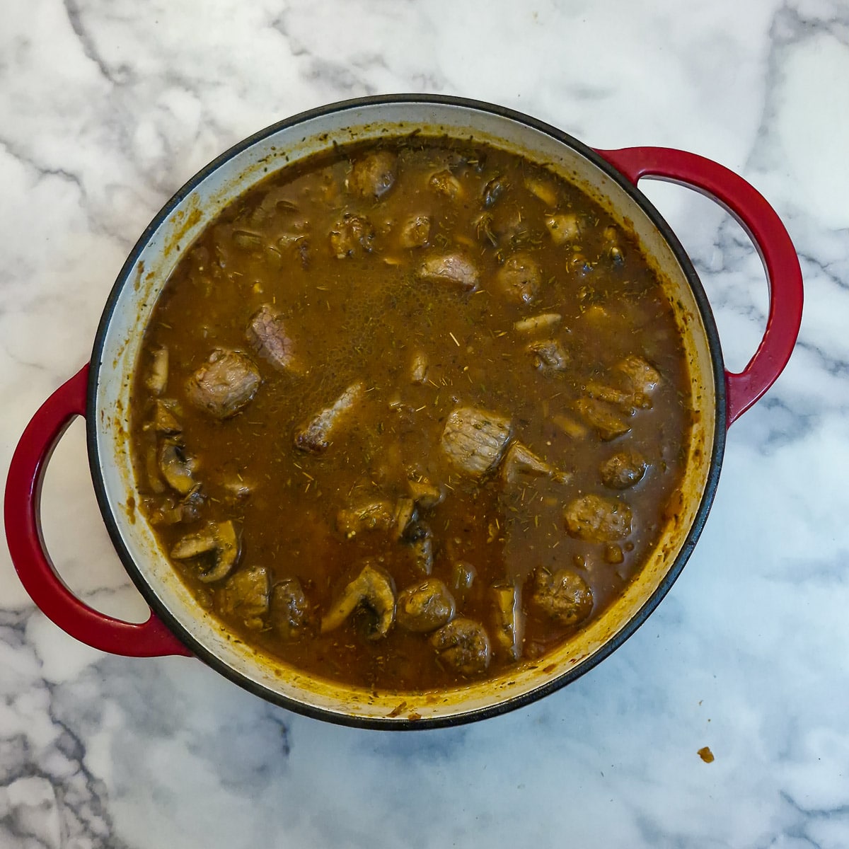 Stock and browned meat pieces added to the casserole.