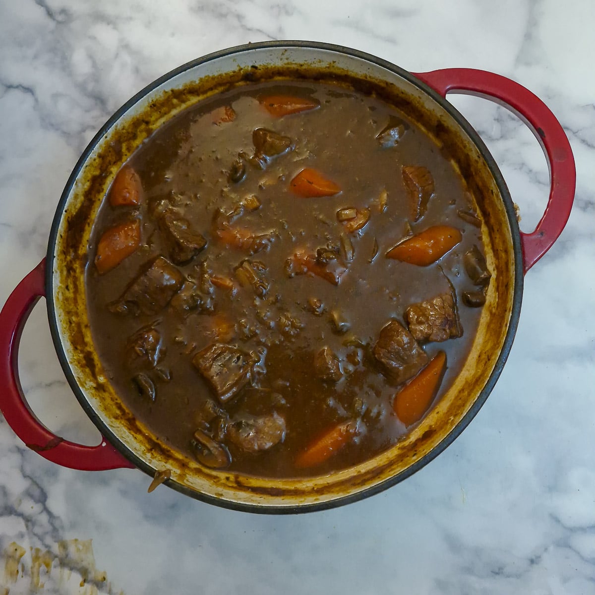 A fully cooked beef stew in a heavy casserole dish.