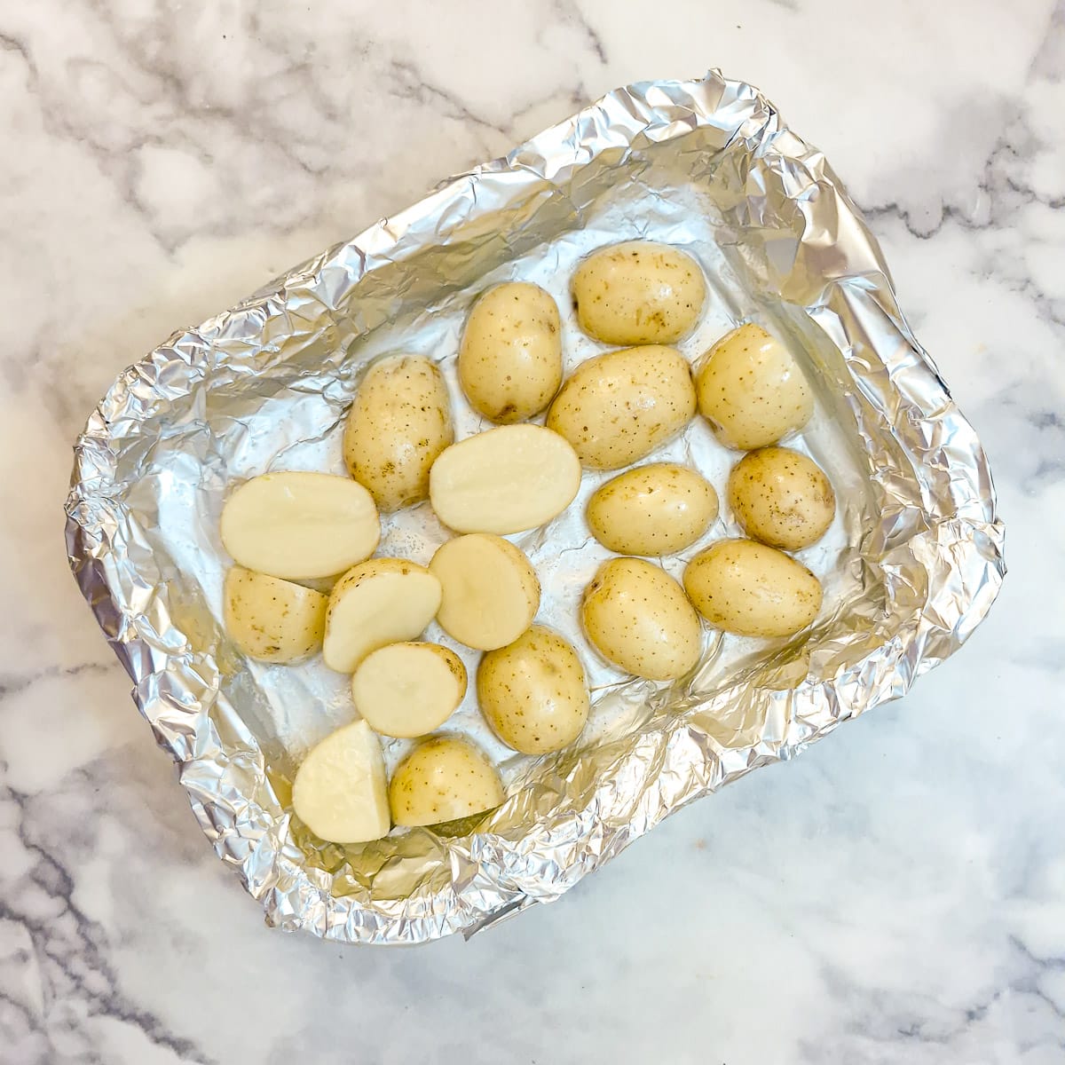 Step 1, halved baby potatoes in a foil-lined baking dish.