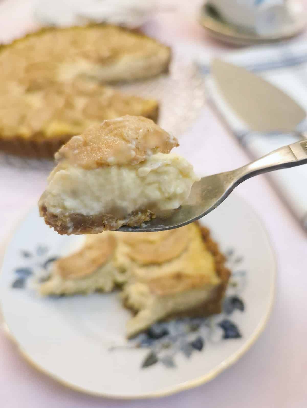 Close up of a forkful of pear and ginger custard tart on a cake fork.