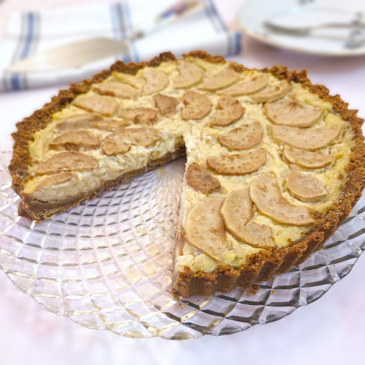 A pear and ginger custart tart on a glass plate with a slice of tart removed to show the filling.