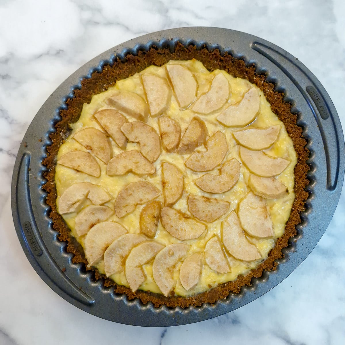 Step 11, a baked pear and ginger custard tart cooling in a round baking tin.
