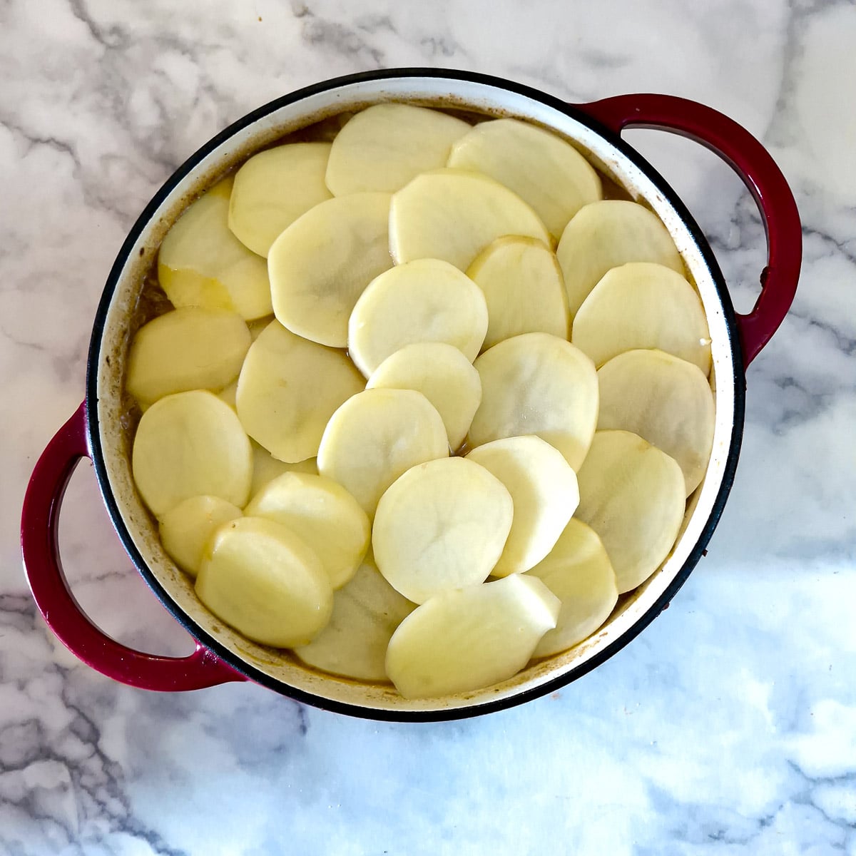Step 9, an overlapping layer of slices potatoes arranged on top of the steak and kidney filling.