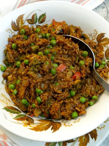 A white autumn leaf-patterned serving dish filled with sweet chilli vegetable rice.