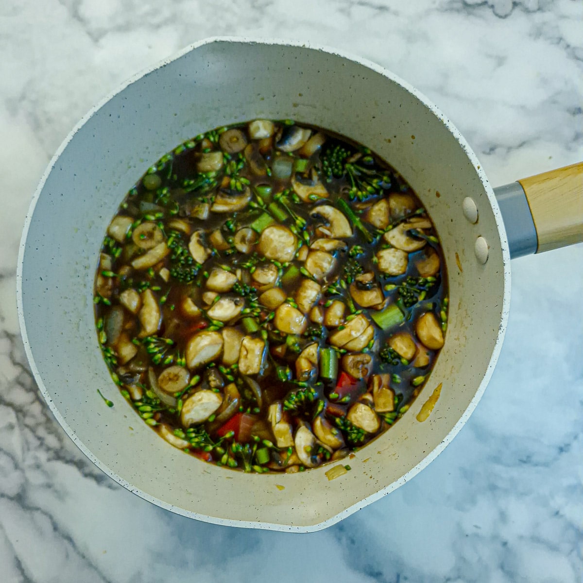 Uncooked rice and stock added to the saucepan.