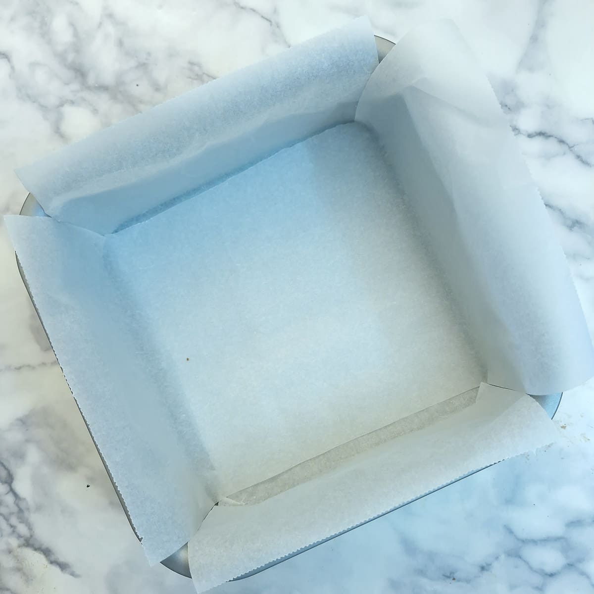 A square baking dish lined with baking parchment.