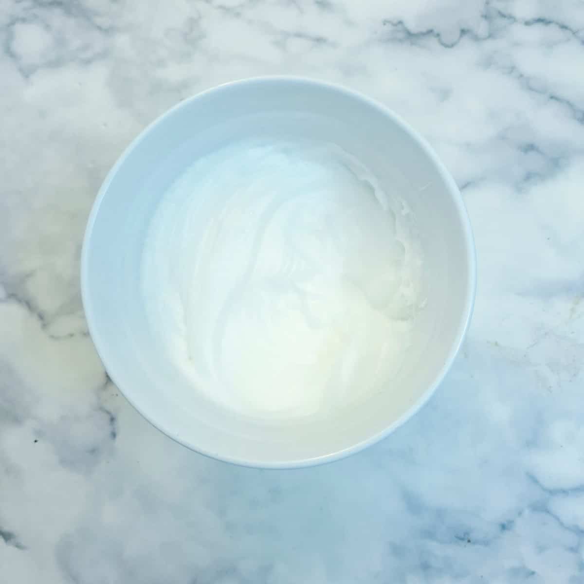 Stifly beaten egg whites in a small bowl.