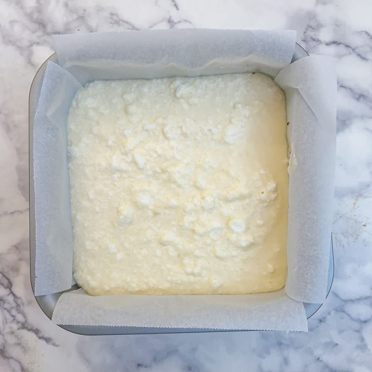 The cake batter poured over caramelised bananas in a square baking dish.