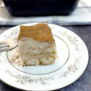 A slice of Baileys milk tart triamisu on a small white plate patterned with blue flowers aroud the edge.