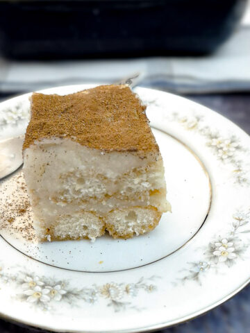 A slice of Baileys milk tart triamisu on a small white plate patterned with blue flowers aroud the edge.