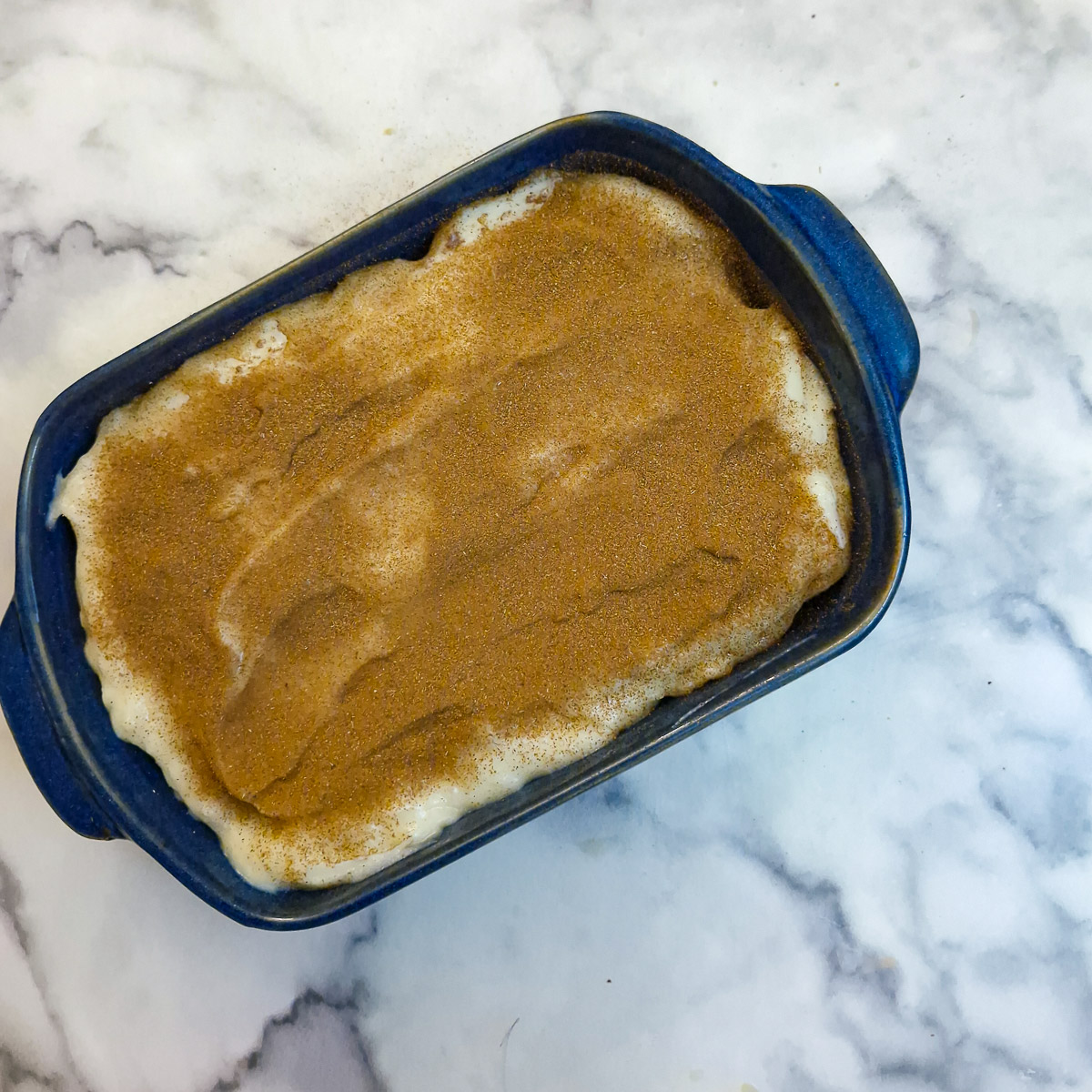 A second layer of custard spread over the biscuits, and dusted with ground cinnamon.