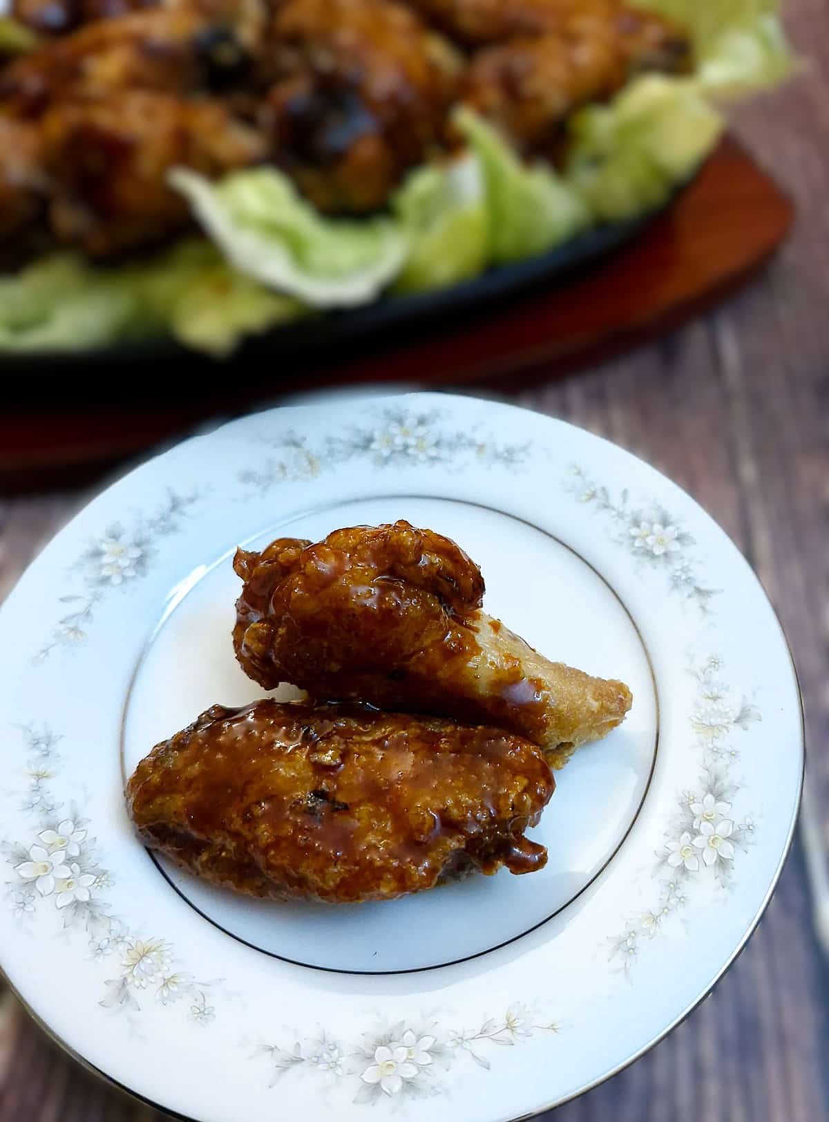 2 gochujang sauce-coated chicken wings on a small plate.