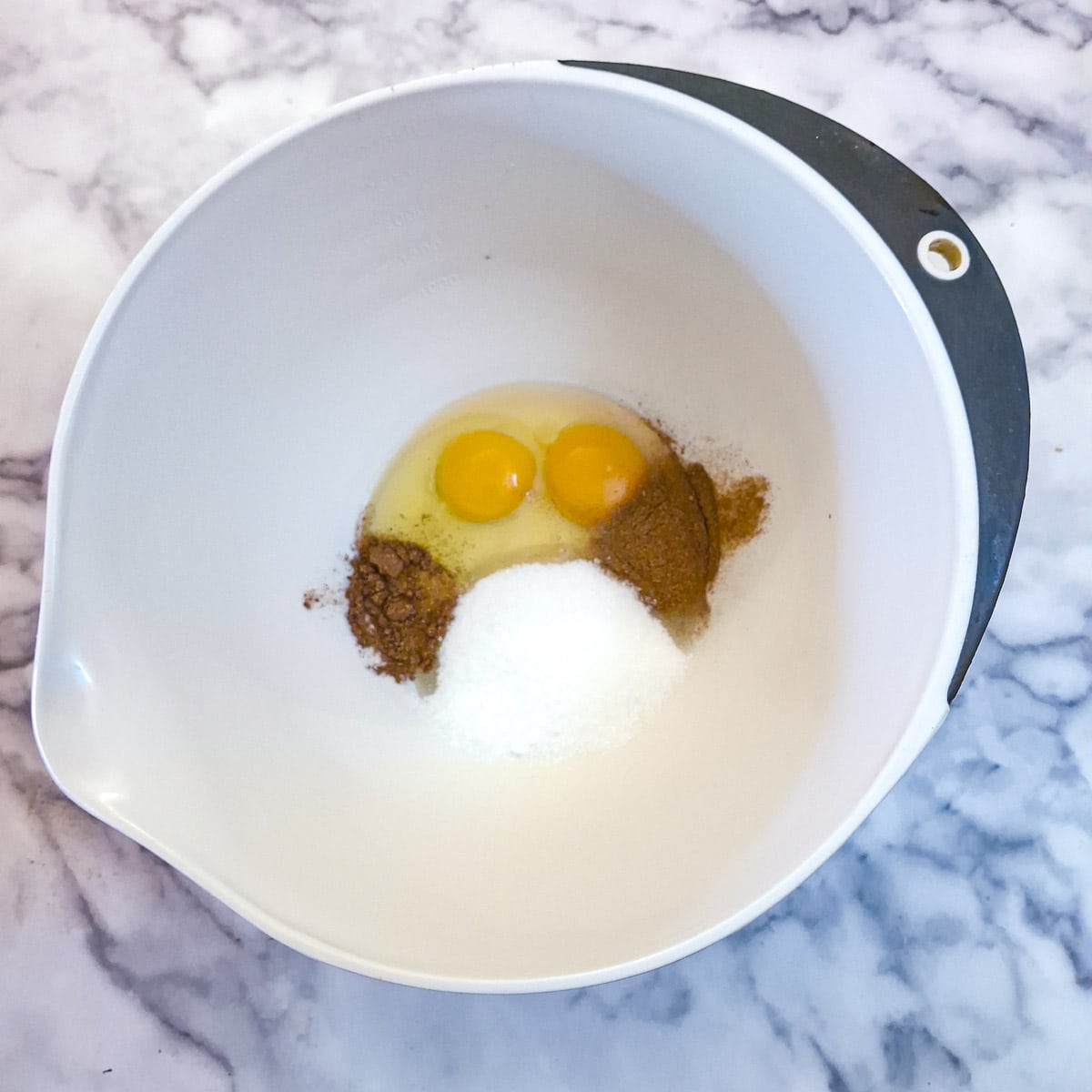 Eggs, sugar and spices in a mixing bowl.