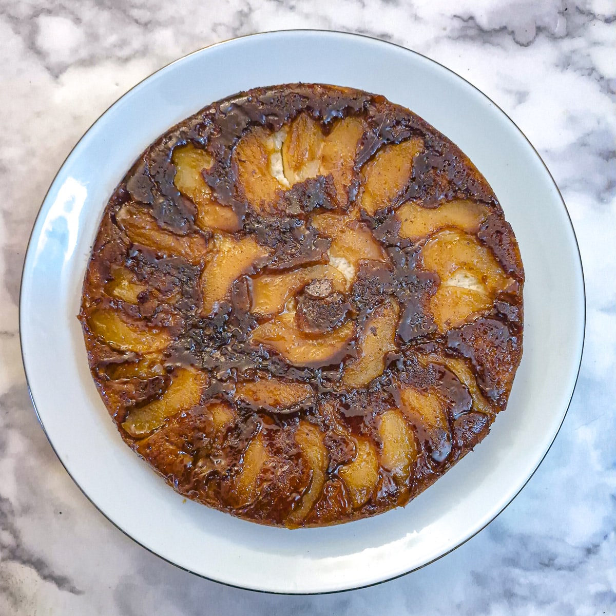 The appoe cake tipped out onto a white plate with the apples now on top.