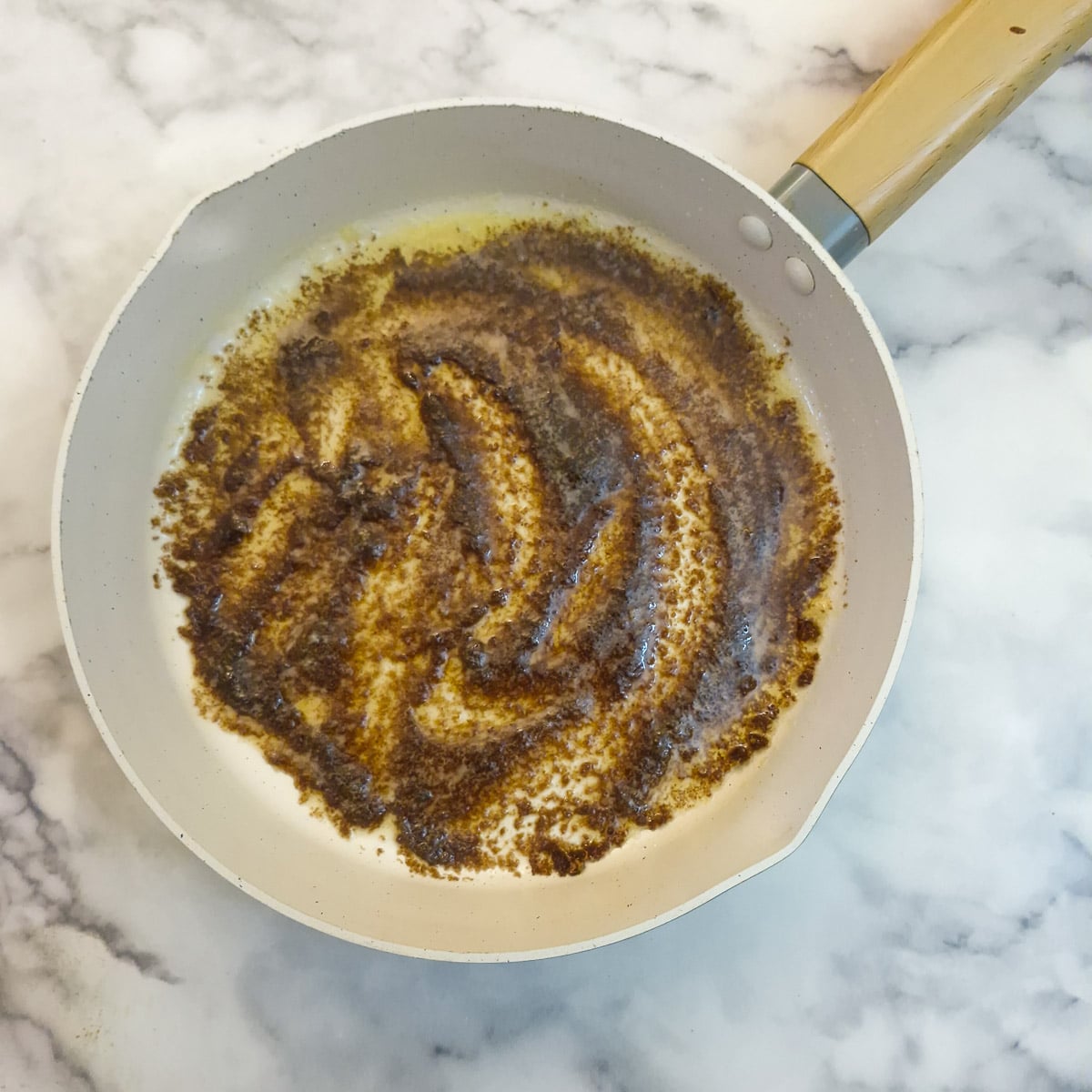 Melted butter and brown suga coating the bottom of a frying pan.
