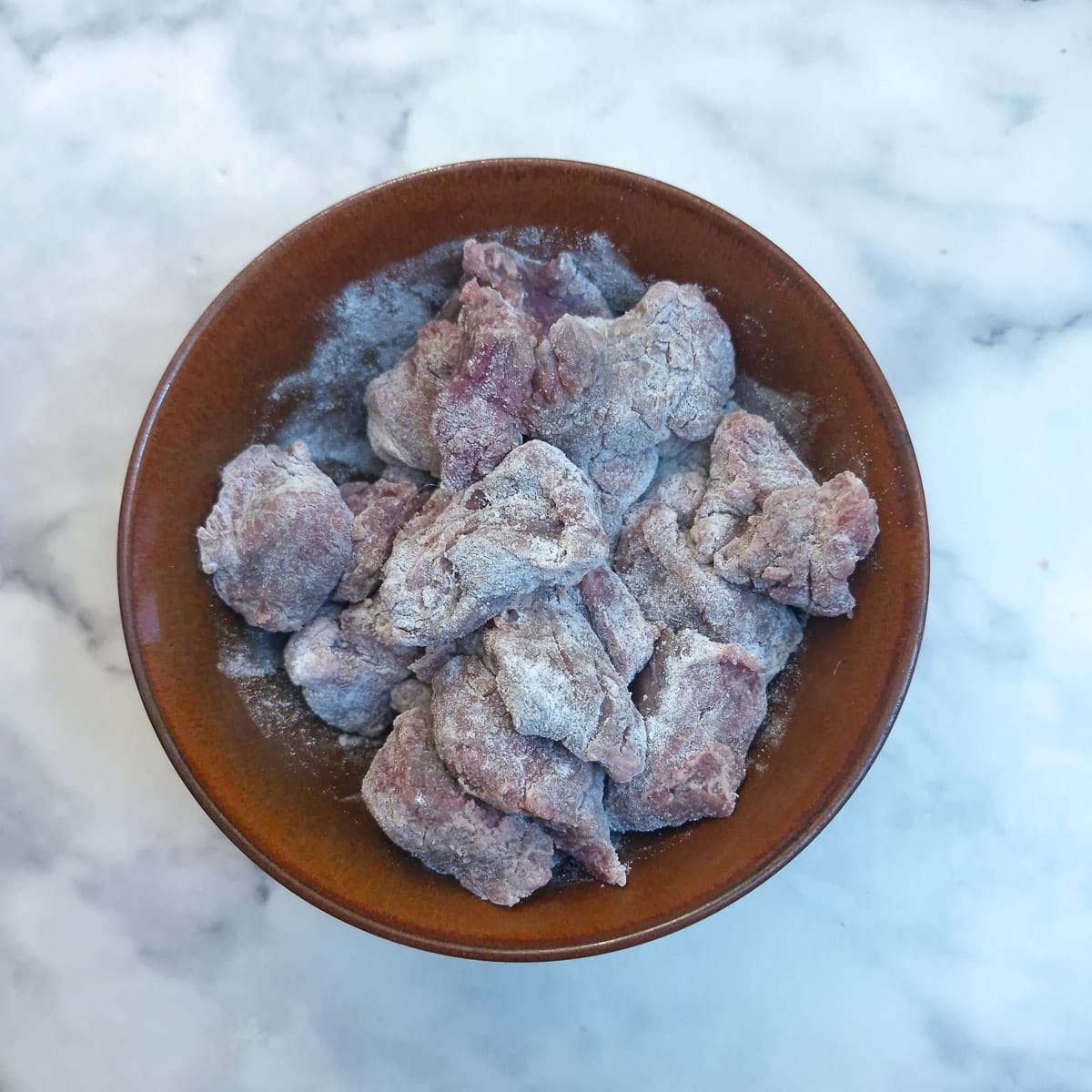 Step 1 - a dish of beef chunks coated in seasoned flour.
