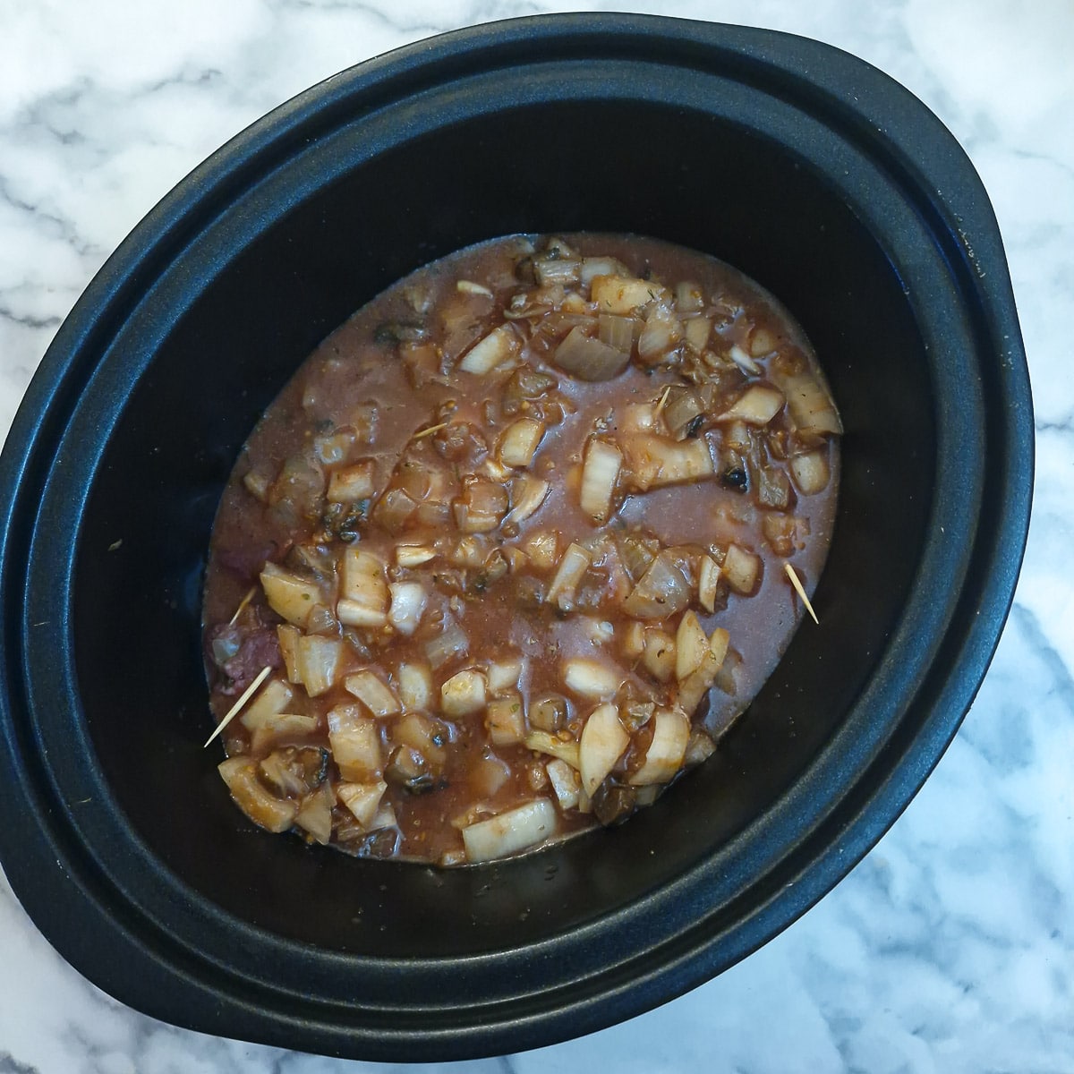Step 9 - gravy ingredients (red wine, passata and chopped onions) poured on top of the beef rolls in the slow cooker.