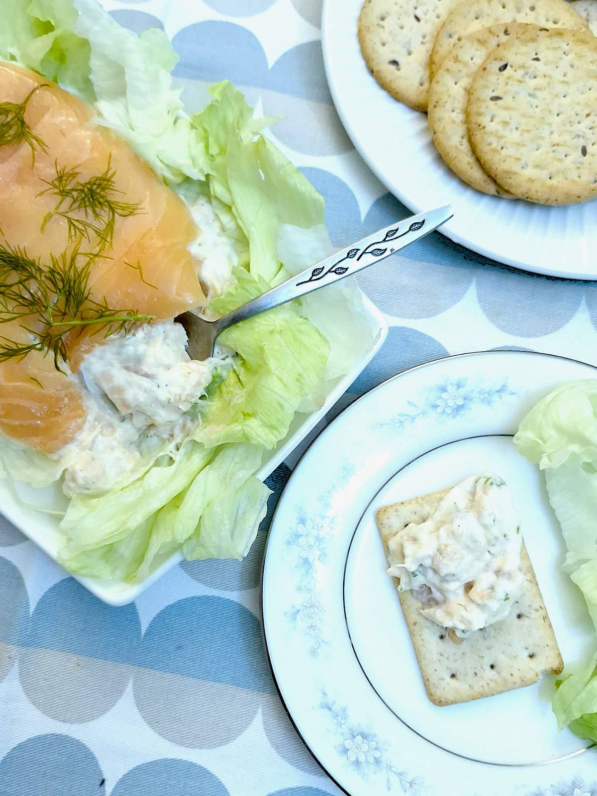 Salmon terrine being spooned onto a small square cracker.