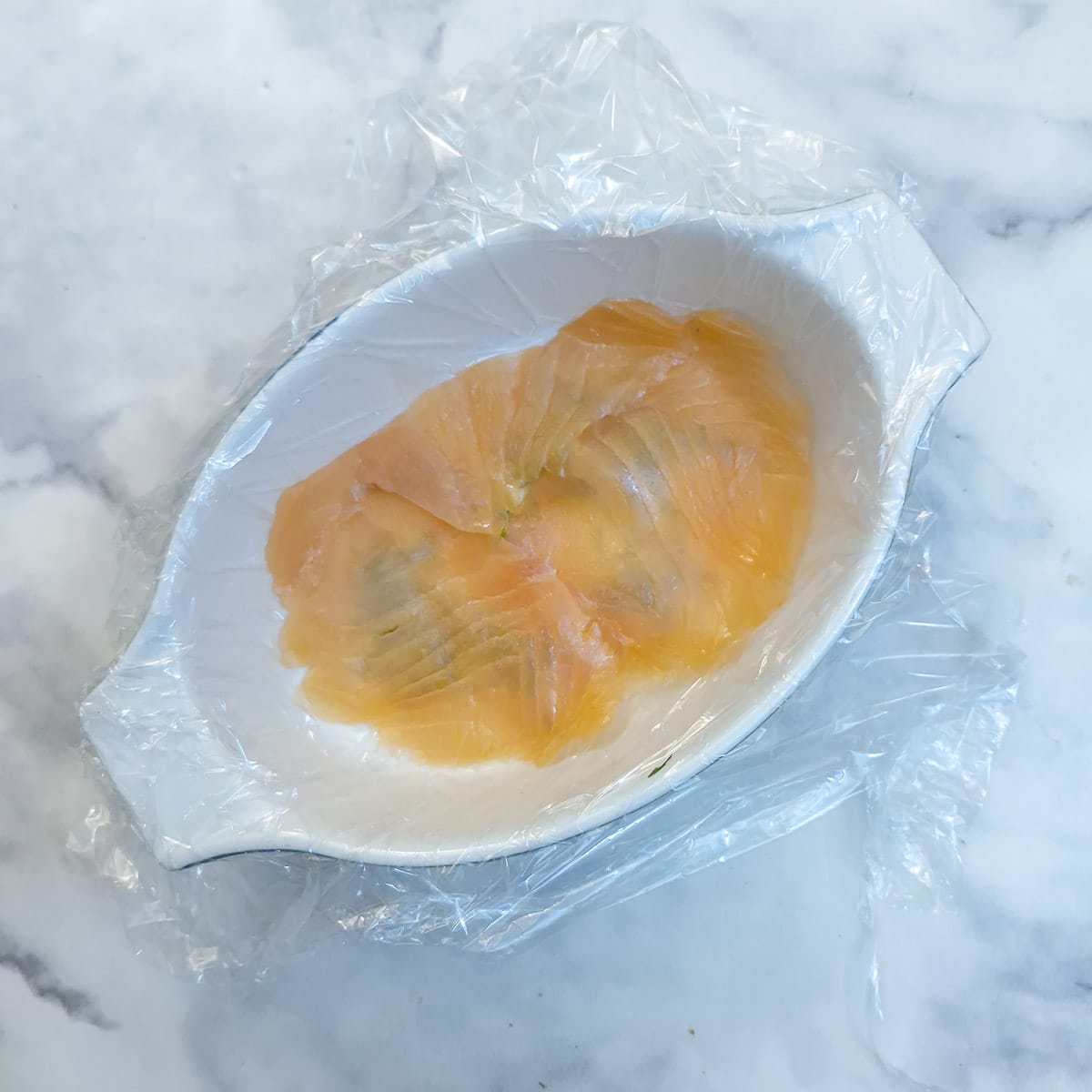 A layer of smoked salmon slices arranged on top of the dill.