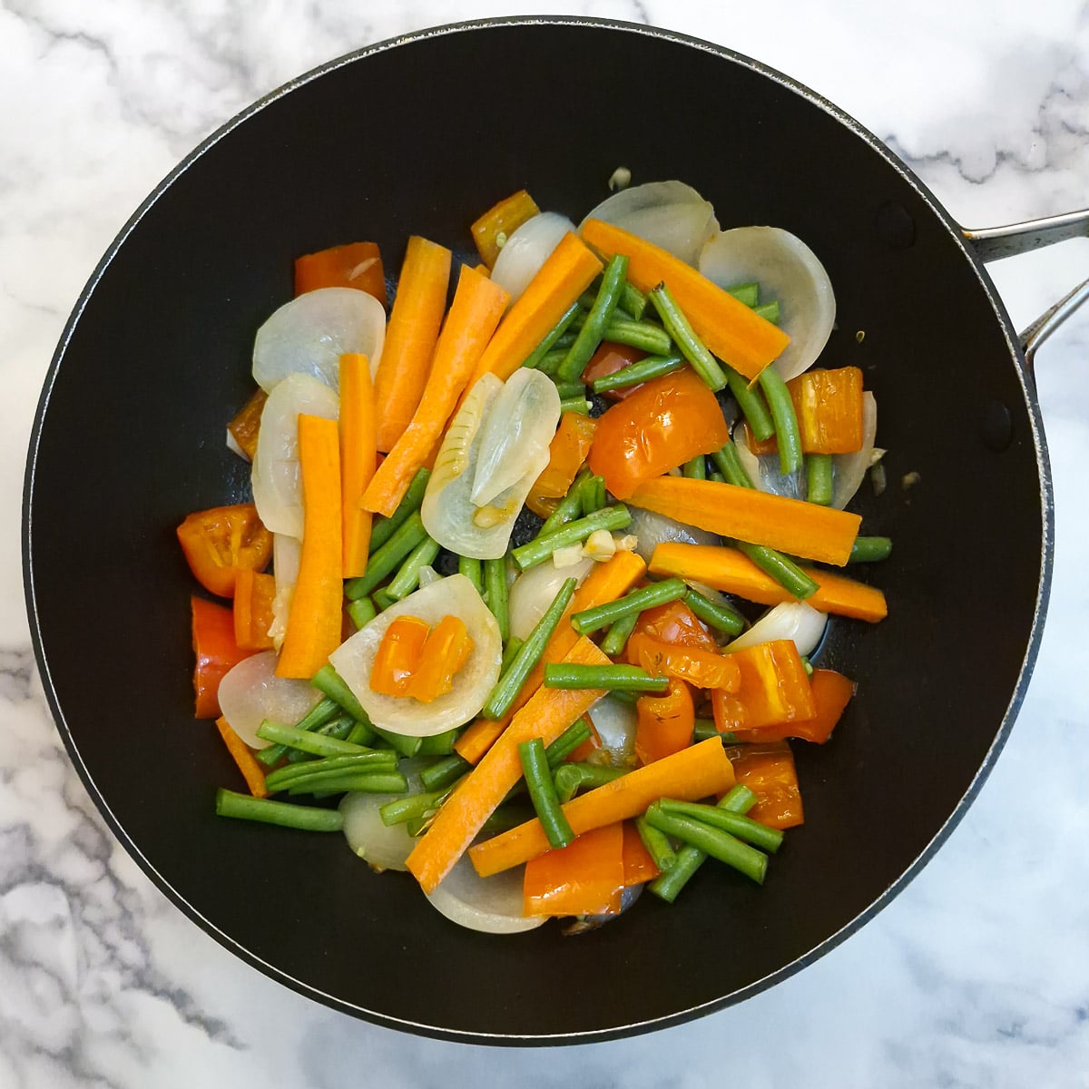 Green beans and carrots added to the onions and red peppers.